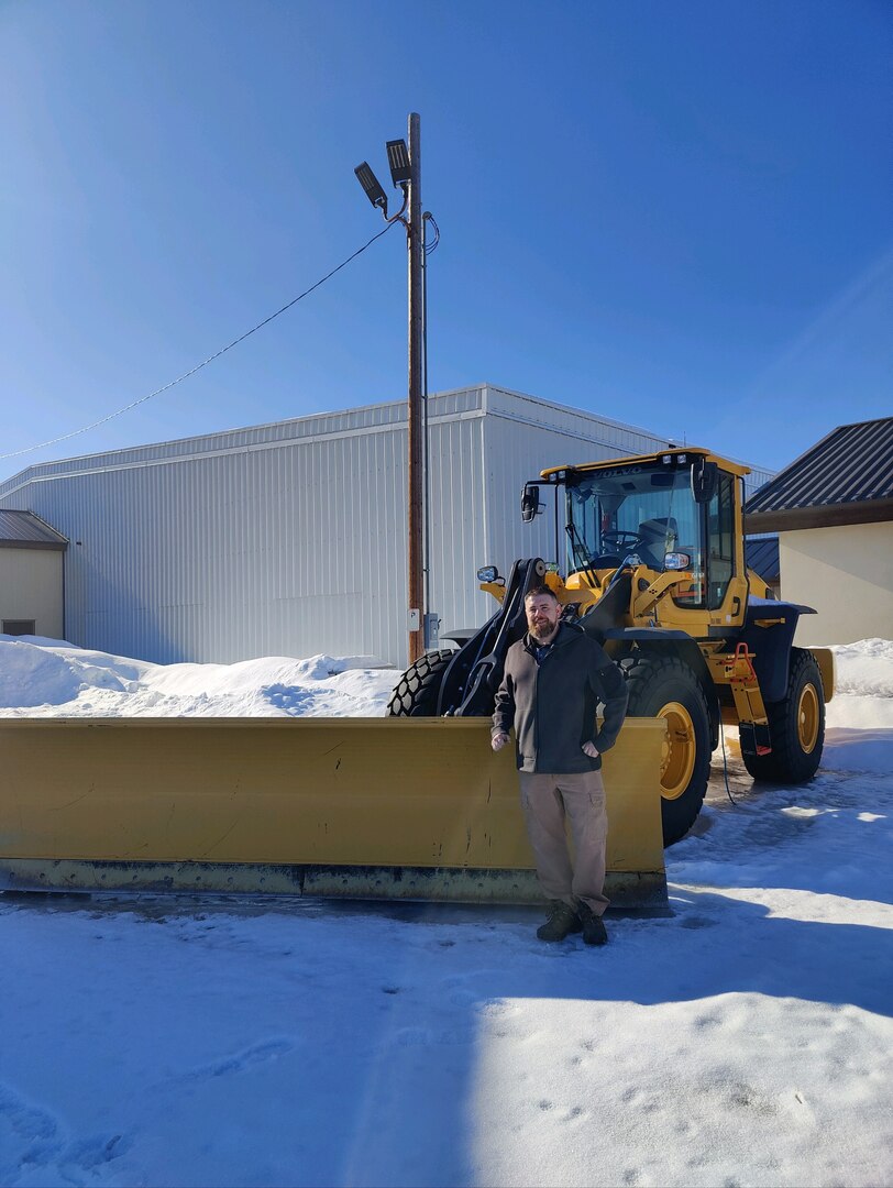 A man poses in front of a tractor.