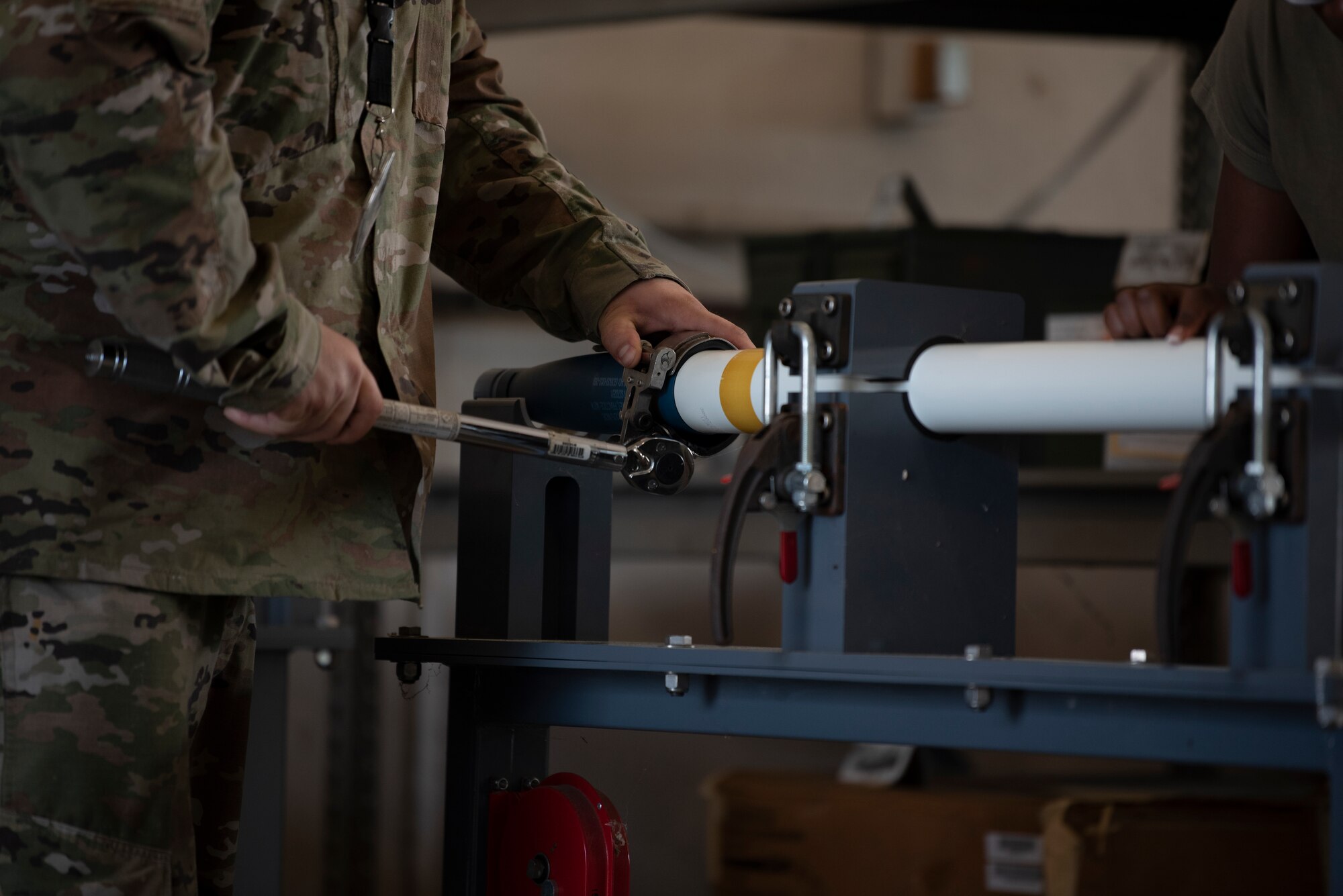 A photo of a person using a wrench to tighten a warhead on a rocket.