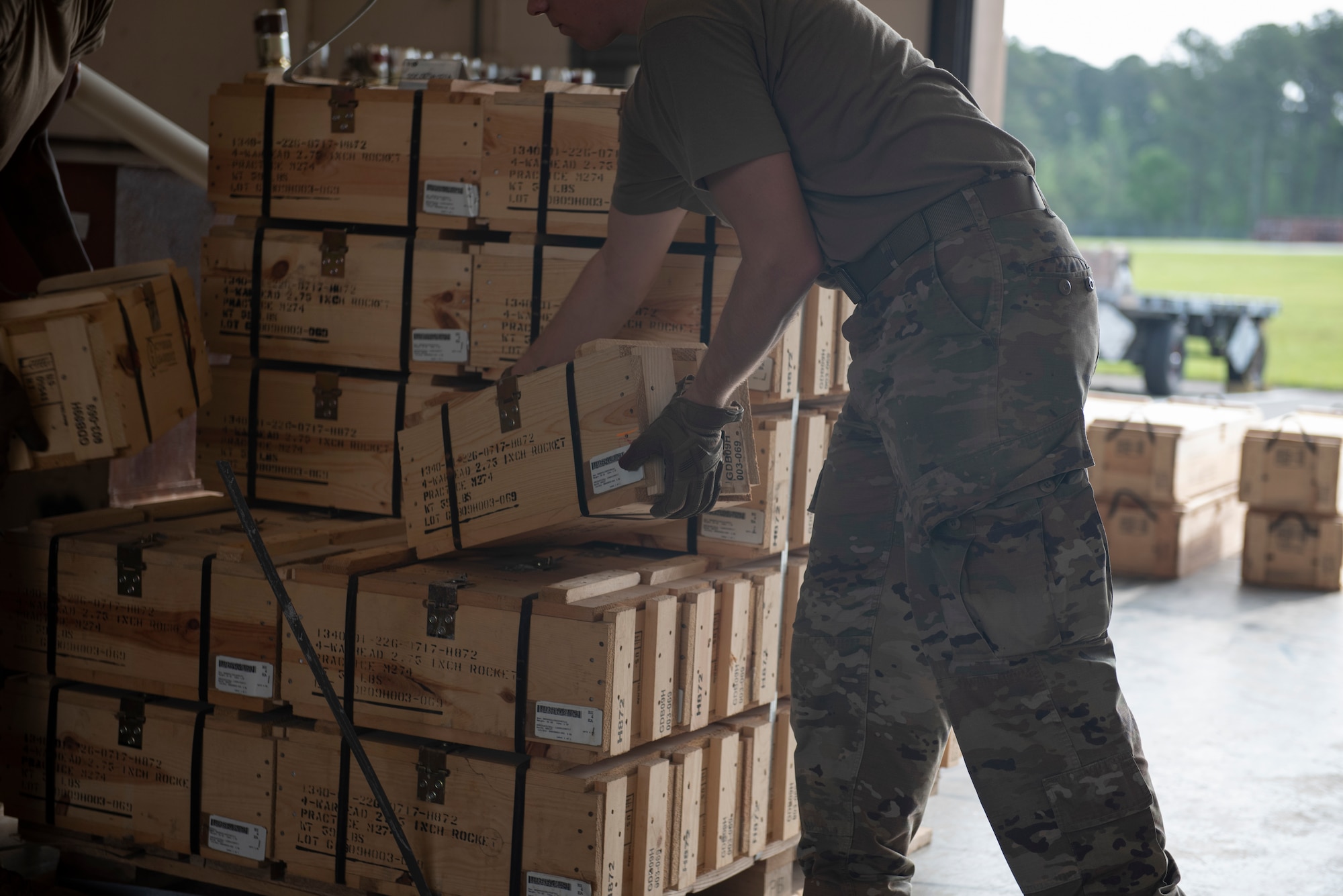 A photo of a person picking up a box out of a bundle of boxes.