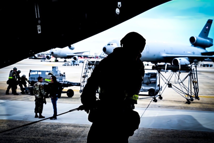 A U.S. Air Force Airman from the 305th Air Mobility Wing wearing mission oriented protective posture gear extends a loading cable inside a C-17 Globemaster III, demonstrating the ability to survive and operate in a contested environment during a readiness exercise at Joint Base McGuire-Dix-Lakehurst, New Jersey, Apr. 4, 2022. Training exercises reinforce Airmen readiness and deliberately strengthen Air Mobility Command’s warfighting culture in order to provide unrivaled Rapid Global Mobility capable of protecting and sustaining the Joint Force.