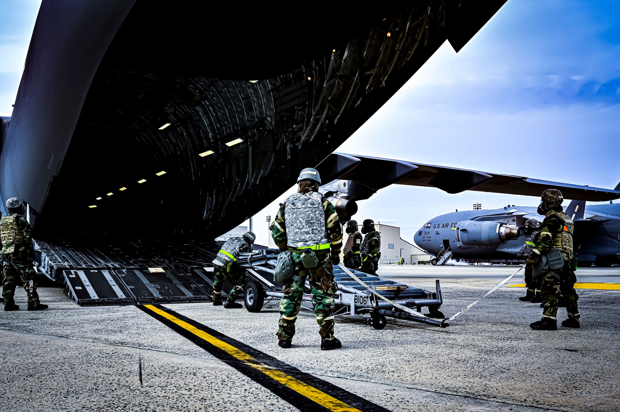 U.S. Air Force Airmen from the 305th Air Mobility Wing wearing mission oriented protective posture gear prepare to upload maintenance equipment onto a C-17 Globemaster III, demonstrating the ability to survive and operate in a contested environment during a readiness exercise at Joint Base McGuire-Dix-Lakehurst, New Jersey, Apr. 4, 2022. Training exercises reinforce Airmen readiness and deliberately strengthen Air Mobility Command’s warfighting culture in order to provide unrivaled Rapid Global Mobility capable of protecting and sustaining the Joint Force.