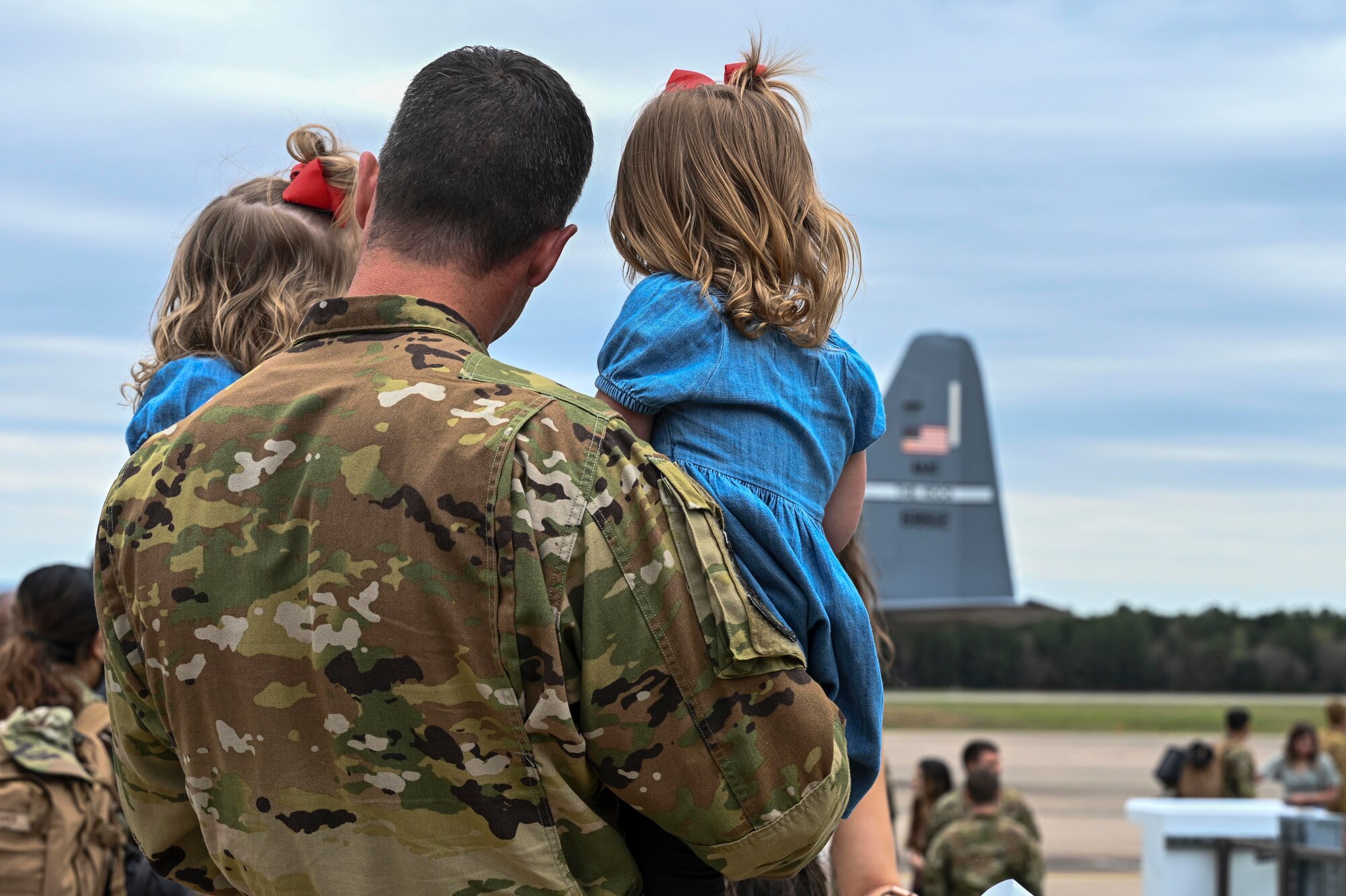 An Airman from the 61st Airlift Squadron reunites with his daughters at Little Rock Air Force Base, Arkansas, after returning from a deployment