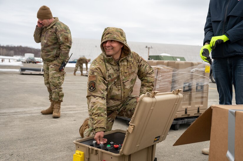 A photo of a service member expanding a solar-powered tent