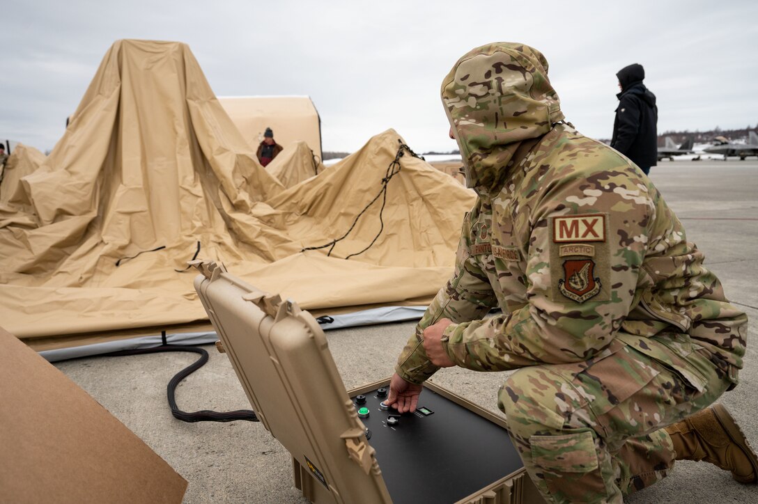 A photo of a service member expanding a solar-powered tent