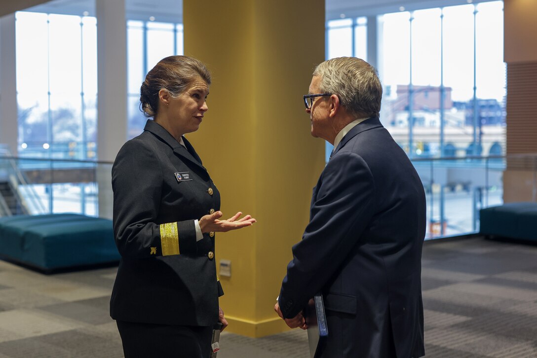Woman in uniform speaks with a man in a business suit (Ohio Governor Mike DeWine).