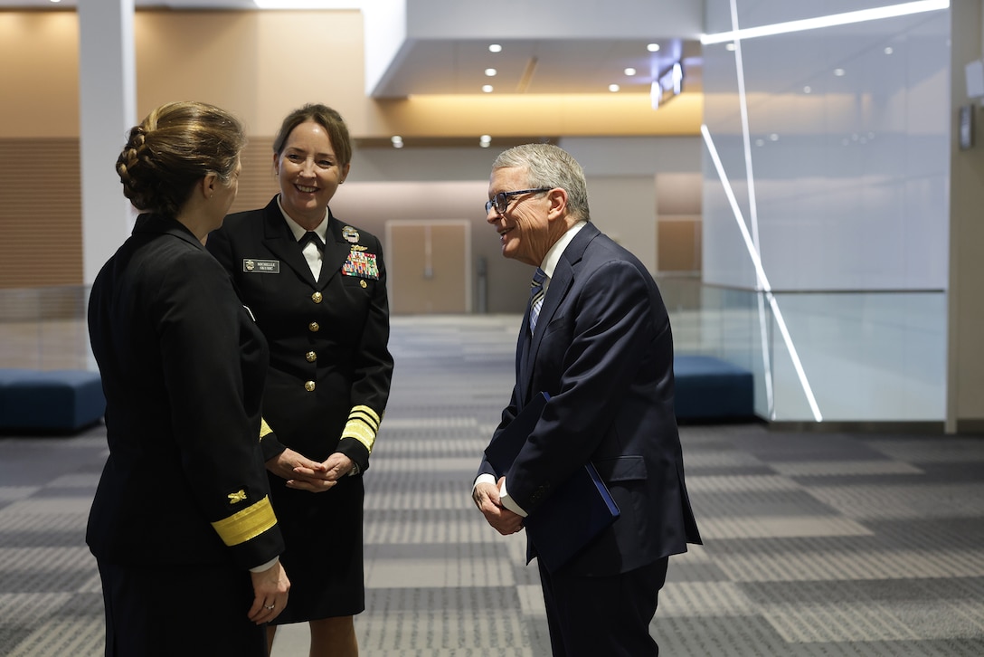 Two women in uniform greet Ohio Governor Mike DeWine. He is in a business suit.