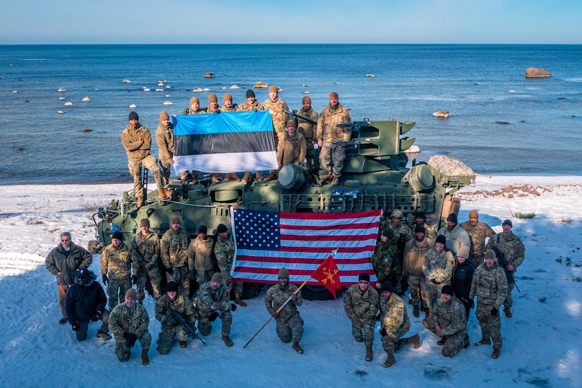 Soldiers pose for a photo on a beach.