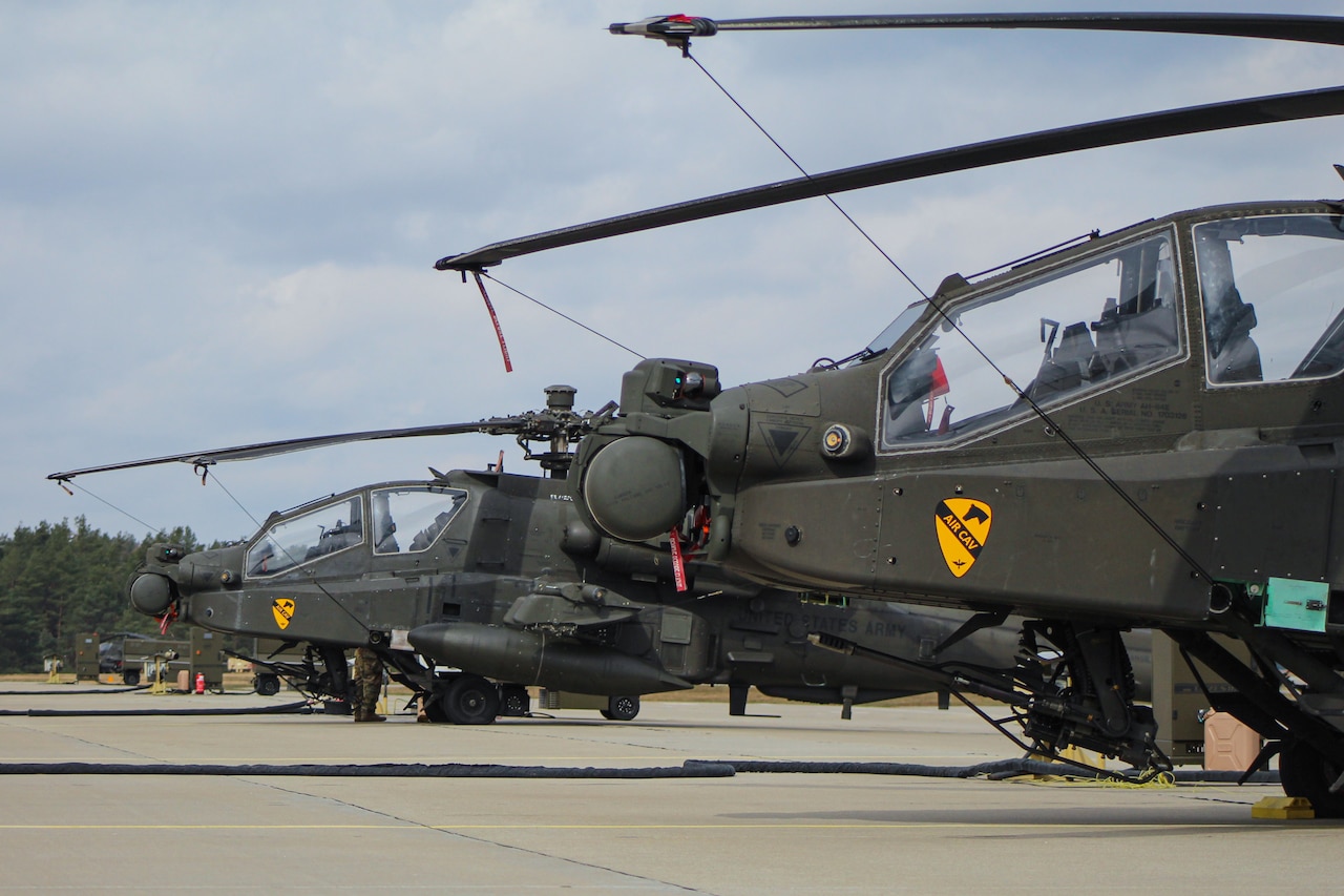 Helicopters sit on a flightline.