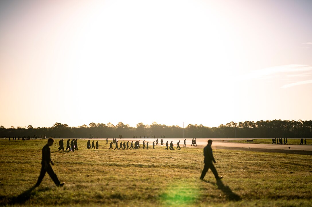 A group of airmen in silhouette walk across a field.