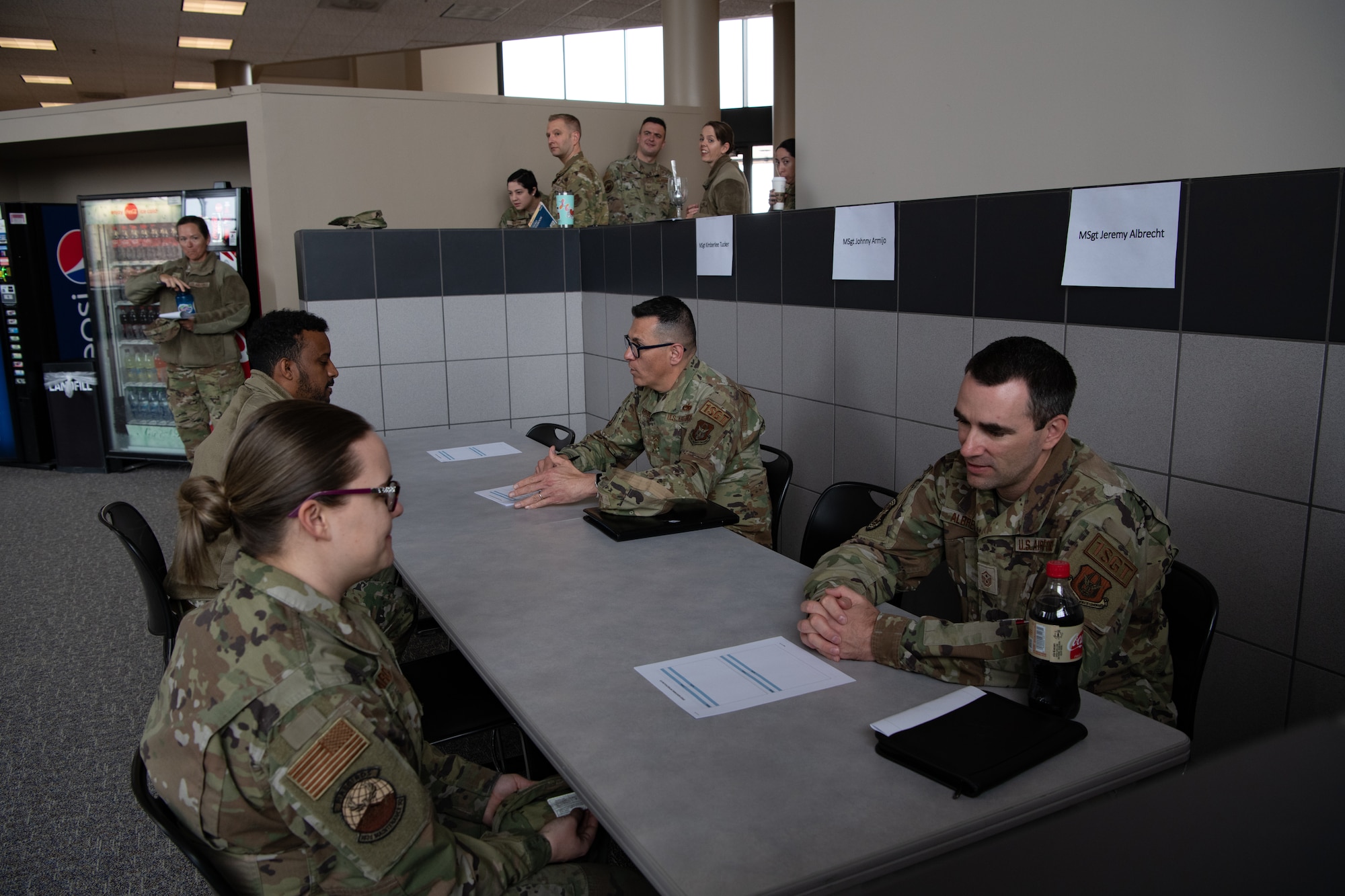 People in military uniform sit at a table having a conversation.