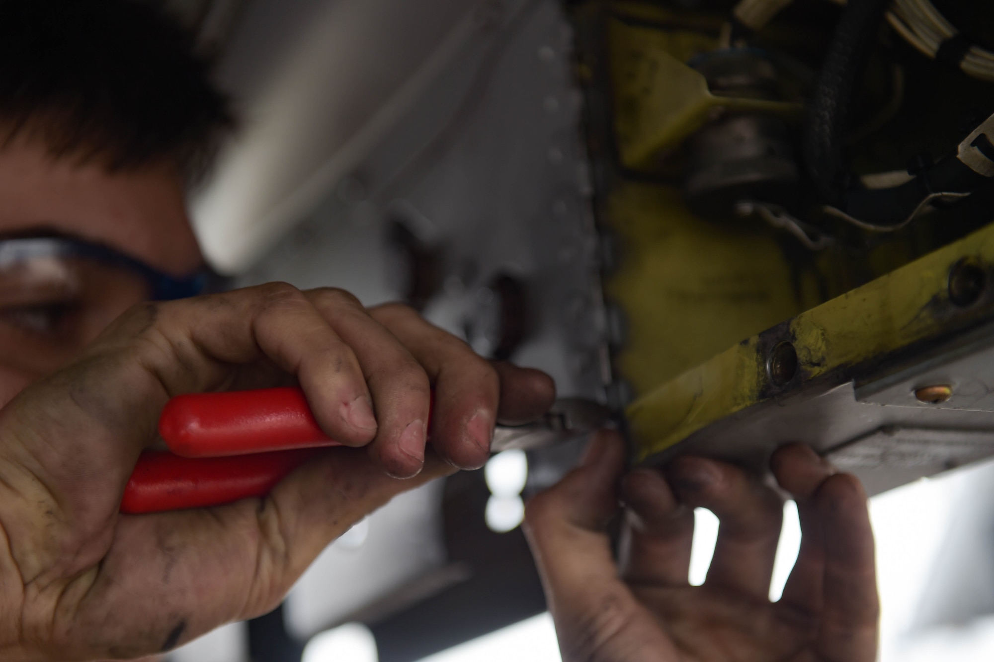 A photo of an Airman gripping pliers.