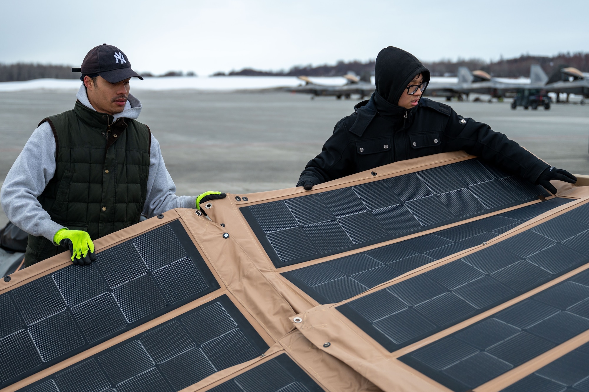 a photo of two people unrolling a sheet of solar panels