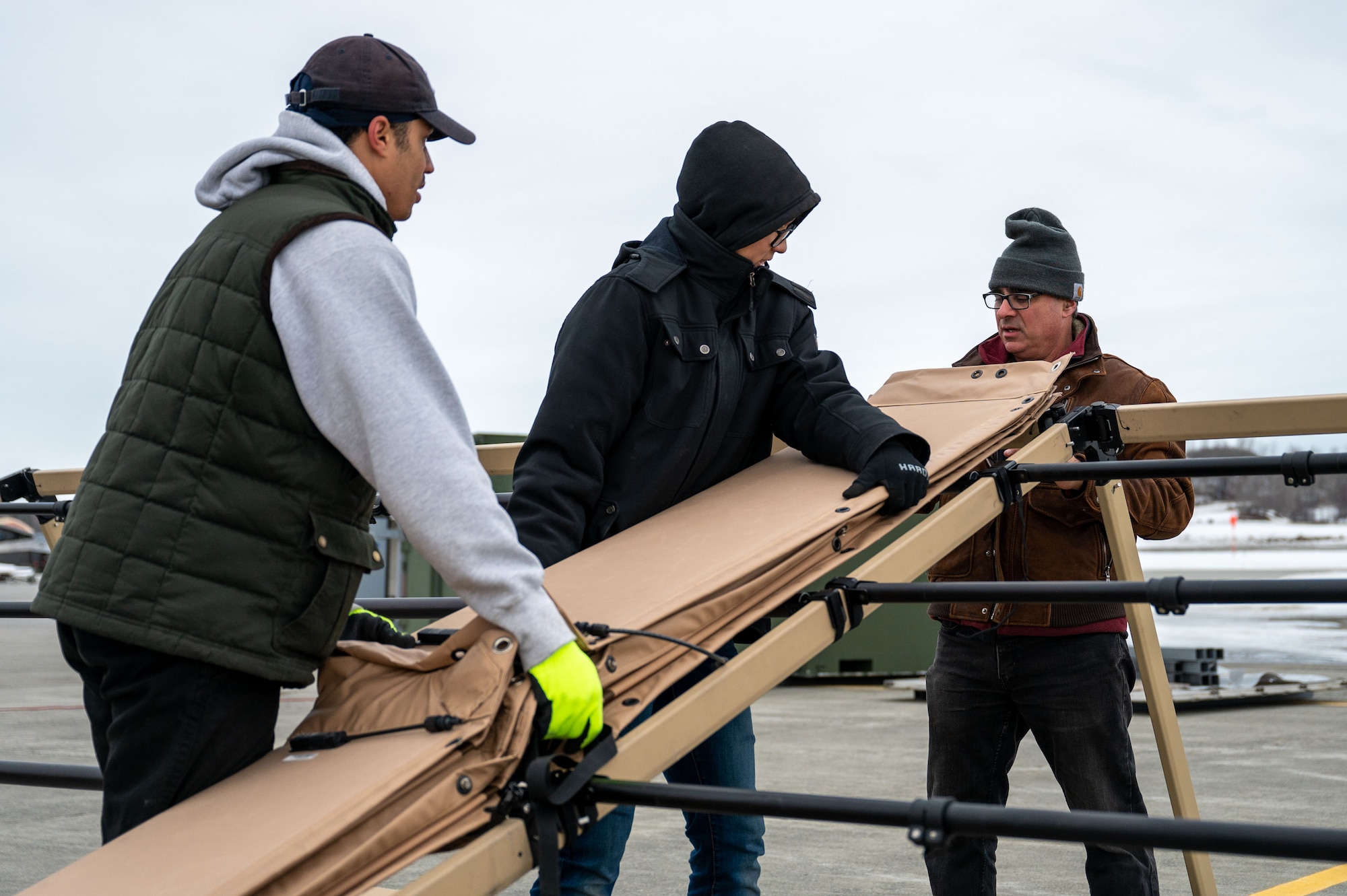 A photo of three people unrolling a sheet of solar panels