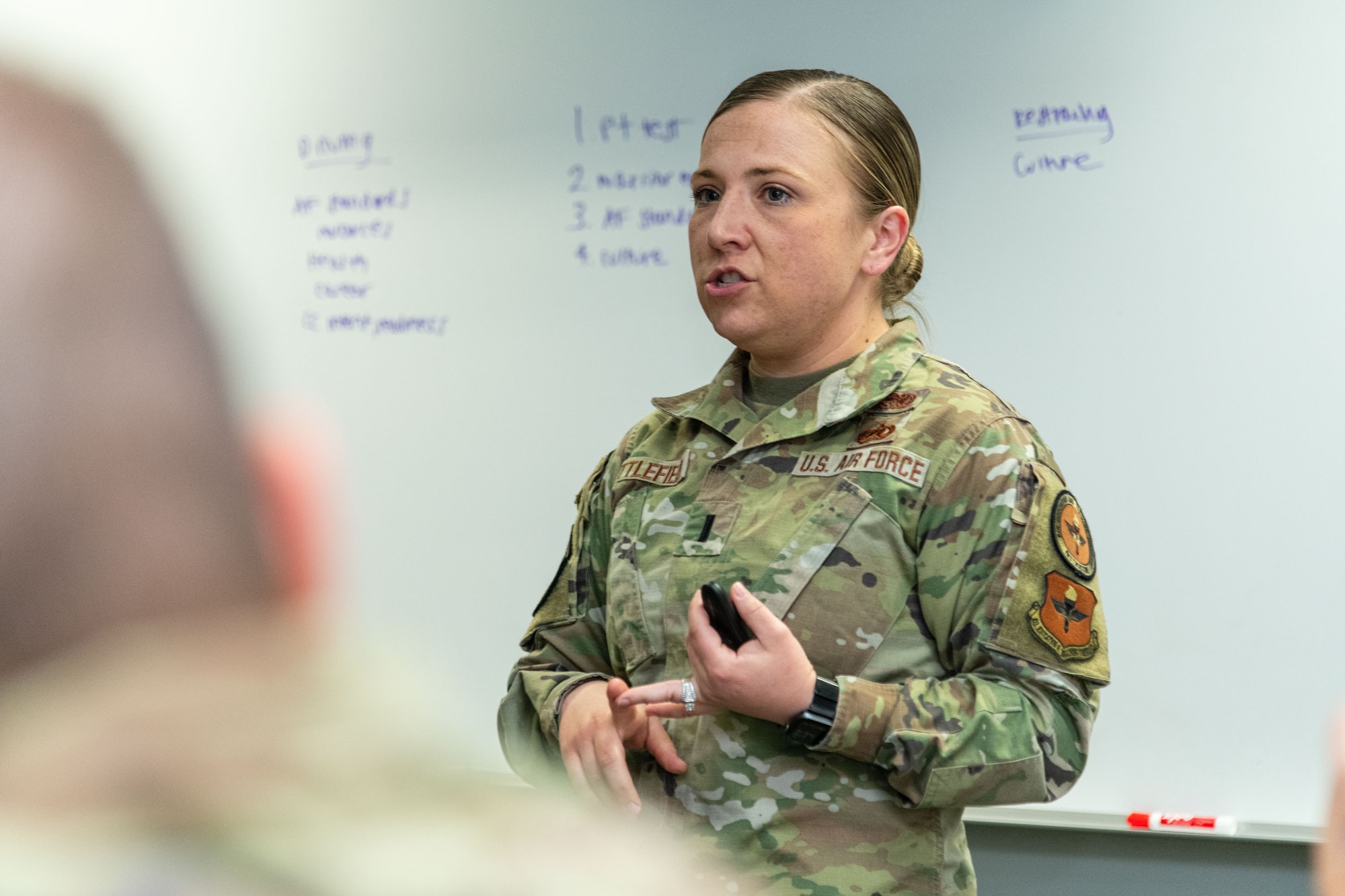 First Lt. Katie Littlefield, 24th Training Squadron Officer Training School instructor, discusses course material with officer trainees during class. Eligible active-duty Line of the Air Force officers can apply for the calendar year 2023 Officer Instructor & Recruiting Special Duty Nomination Board April 11 to May 14. (U.S. Air Force photo by Trey Ward)