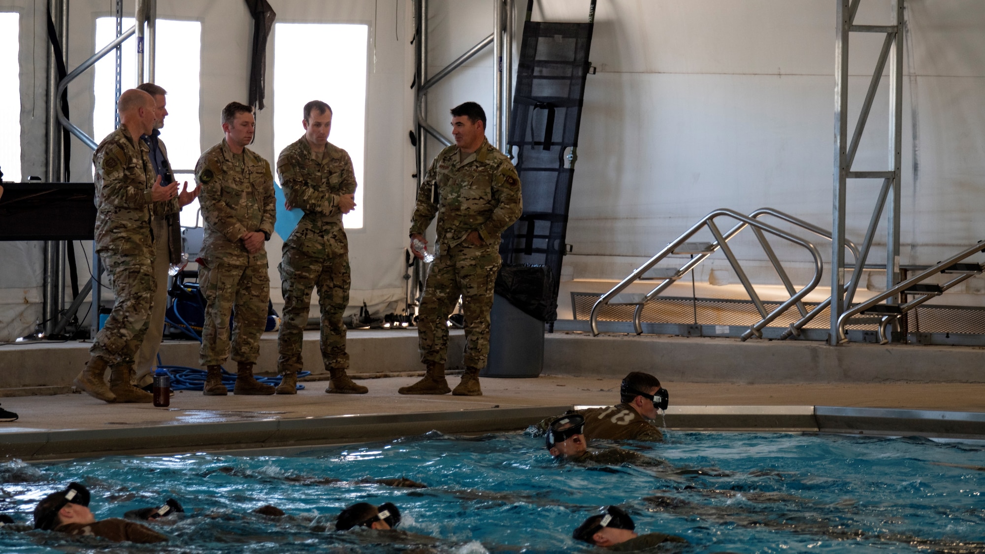 U.S. Air Force Maj. Gen. Matthew Davidson (far right), Air Force Special Operations Command director of operations, discusses aspects of Assessment and Selection with Col. Mason Dula (far left), SWTW commander, at Chaparral Pool on Joint Base San Antonio-Lackland, Texas, Mar. 15, 2022. One third of graduates from the Special Warfare Training Wing pipelines will feed directly into operational AFSOC units, to include Combat Controllers, Special Reconnaissance Airmen, Special Tactics Officers, and some Pararescuemen.