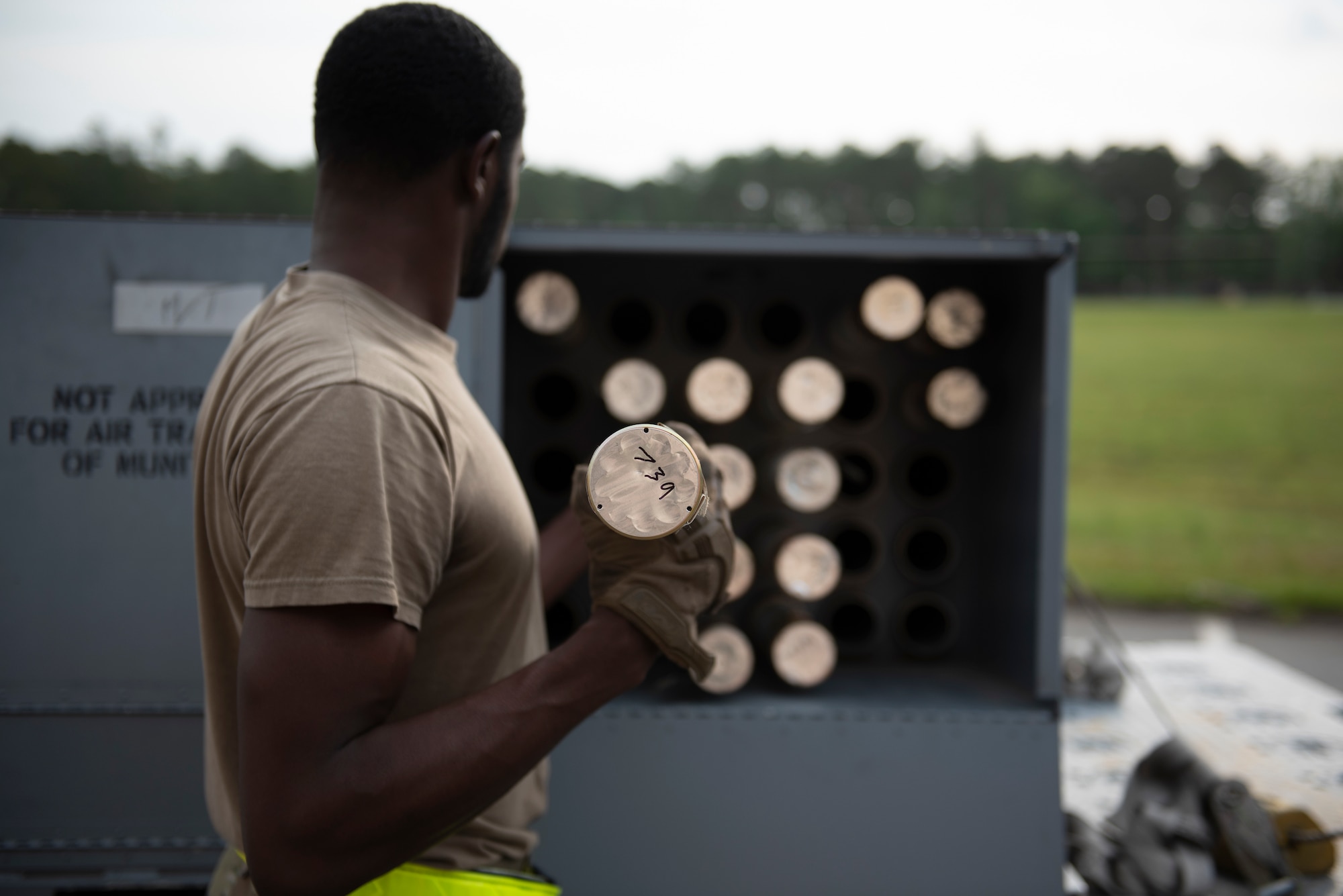 A photo of a person loading a rocket into a container full of other rockets.