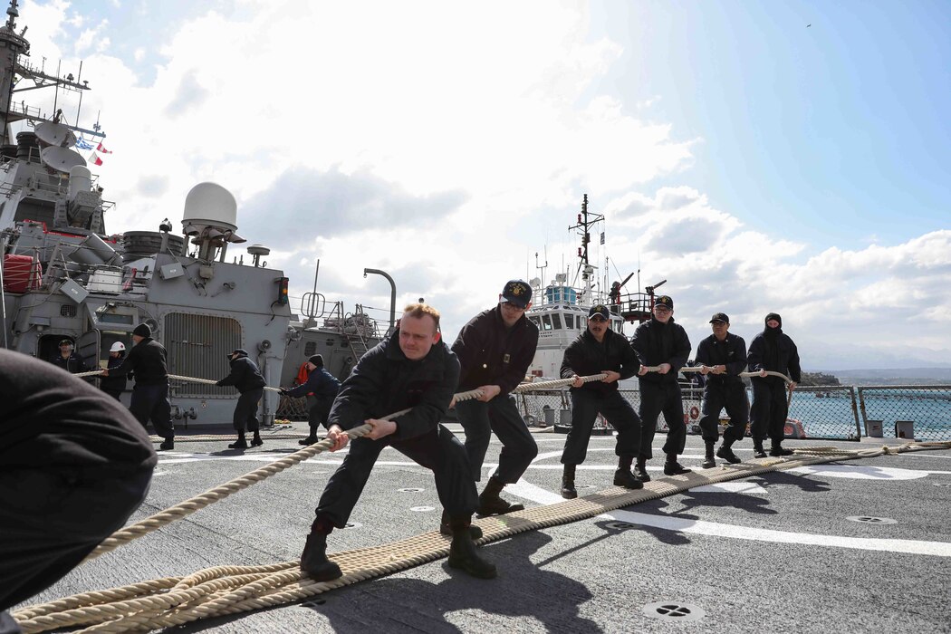 Sailors assigned to the Arleigh Burke-class guided-missile destroyer USS Ross (DDG 71) are lined up and pulling on a mooring line as the ship enters port in Souda Bay, Greece, March 24, 2022.