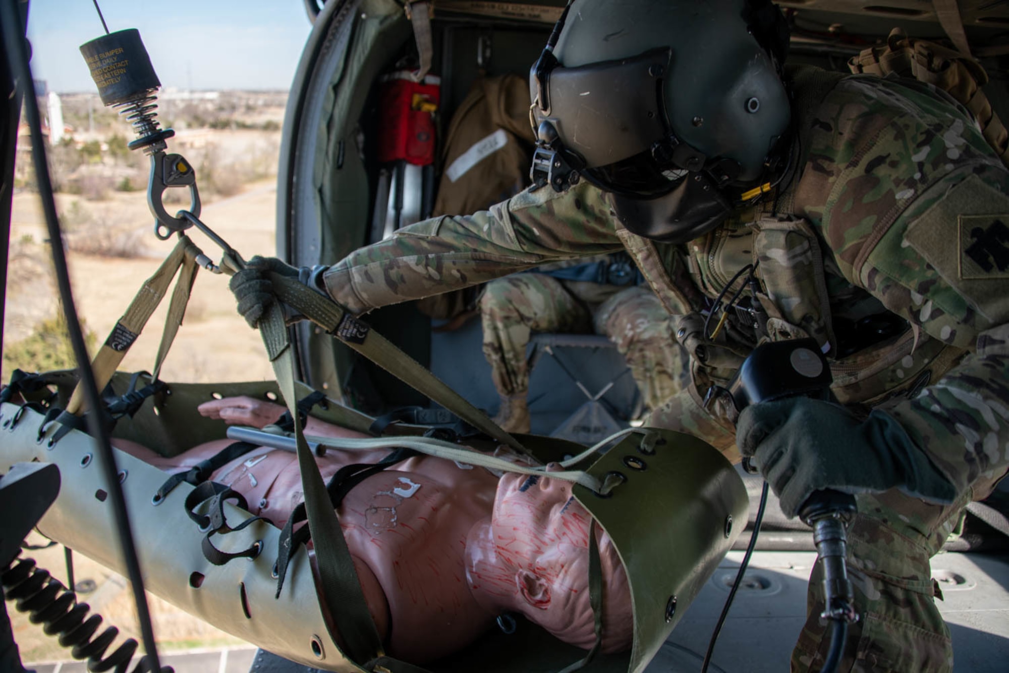 Soldier loads mannequin onto helicopter via winch