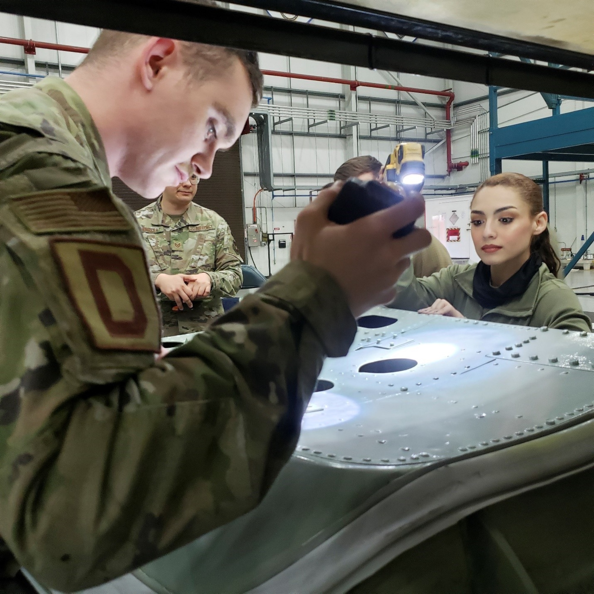 U.S. Air Force Senior Airman Colby Cranney, left, 100th Maintenance Squadron aircraft structural maintenance journeyman, teaches U.S. Air Force Airman 1st Class Alexis Garza, right, 100th Maintenance Squadron aircraft structural maintenance apprentice how to perform a critical corrosion inspection on a KC-135 Stratotanker panel at Royal Air Force Mildenhall, England, March 29, 2022. The structural maintenance section is responsible for performing preventative actions to preserve the lifespan of assigned aircraft. (U.S Air Force photo by Staff Sgt. Tarelle Walker)