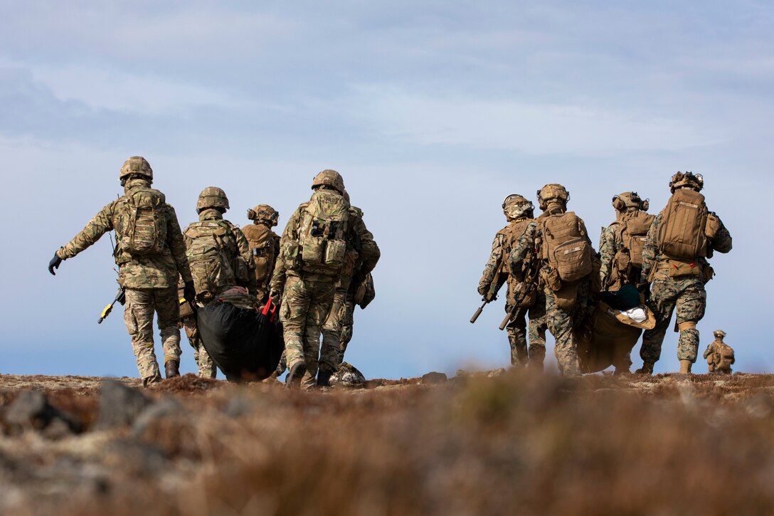 U.S. Marines and Sailors assigned to 22nd Marine Expeditionary Unit and Royal Marine Commandos assigned to M Company, 42 Commando Royal Marines move simulated casualties during a tactical recovery of aircraft and personnel exercise in support of Northern Viking 2022 on Keflavik Airbase, Iceland, April 8, 2022. Northern Viking 22 strengthens interoperability and force readiness between the U.S., Iceland and Allied nations, enabling multi-domain command and control of joint and coalition forces in the defense of Iceland and Sea Lines of Communication in the Greenland, Iceland, United Kingdom (GIUK) gap. (U.S. Marine Corps photo by Cpl. Yvonna Guyette)