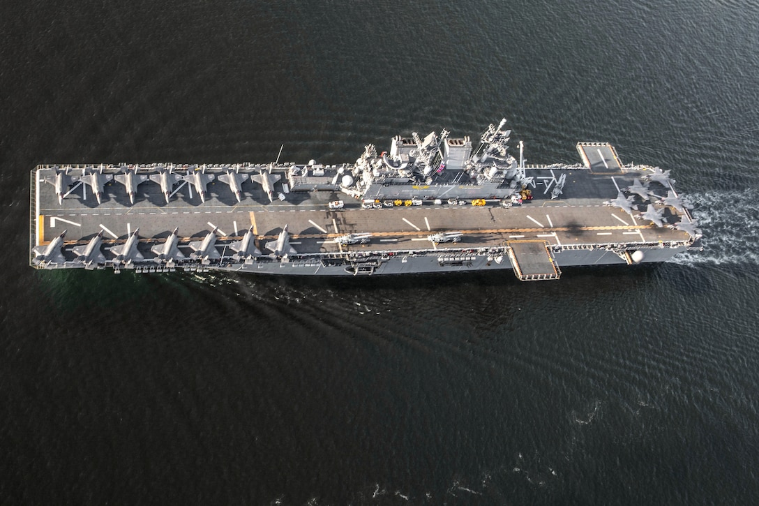 View from overhead of a ship's deck with multiple aircraft parked in rows.