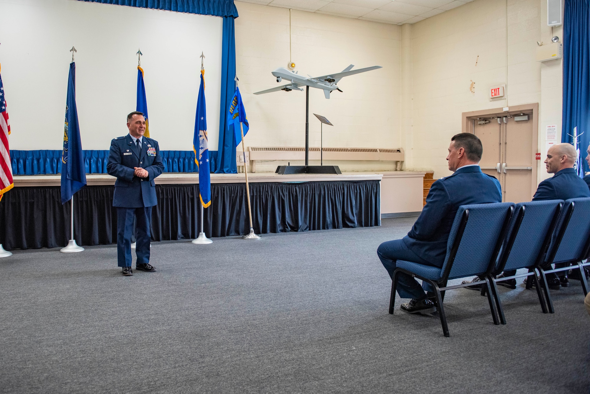 A Man iun dress blues speaks in an auditorium.