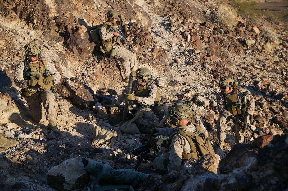 U.S. Marines with 1st Battalion, 2d Marine Regiment, 2d Marine Division (MARDIV), wait to advance during Weapons and Tactics Instructor (WTI) course on Marine Corps Air Station Yuma, Arizona, March 30, 2022. WTI is a seven-week training event, hosted by Marine Aviation Weapons and Tactics Squadron One (MAWTS-1), which emphasizes the development of small task-organized unit experimentation across all warfighting functions, as well as enhance the battalion's ability to conduct command and control, fire-support planning, intelligence functions, and logistical support to distributed company level operations. This exercise continues support of 2d MARDIV's experimental battalion's assessment and mission essential task list-based pre-deployment training progression. (U.S. Marine Corps photo by Pfc. Sarah Pysher)