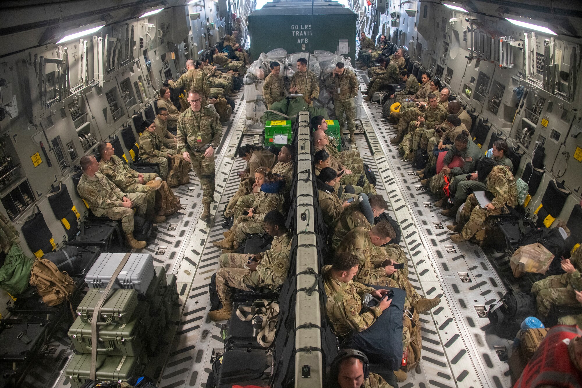 a large group of airmen sit in the cargo hold of an airplane