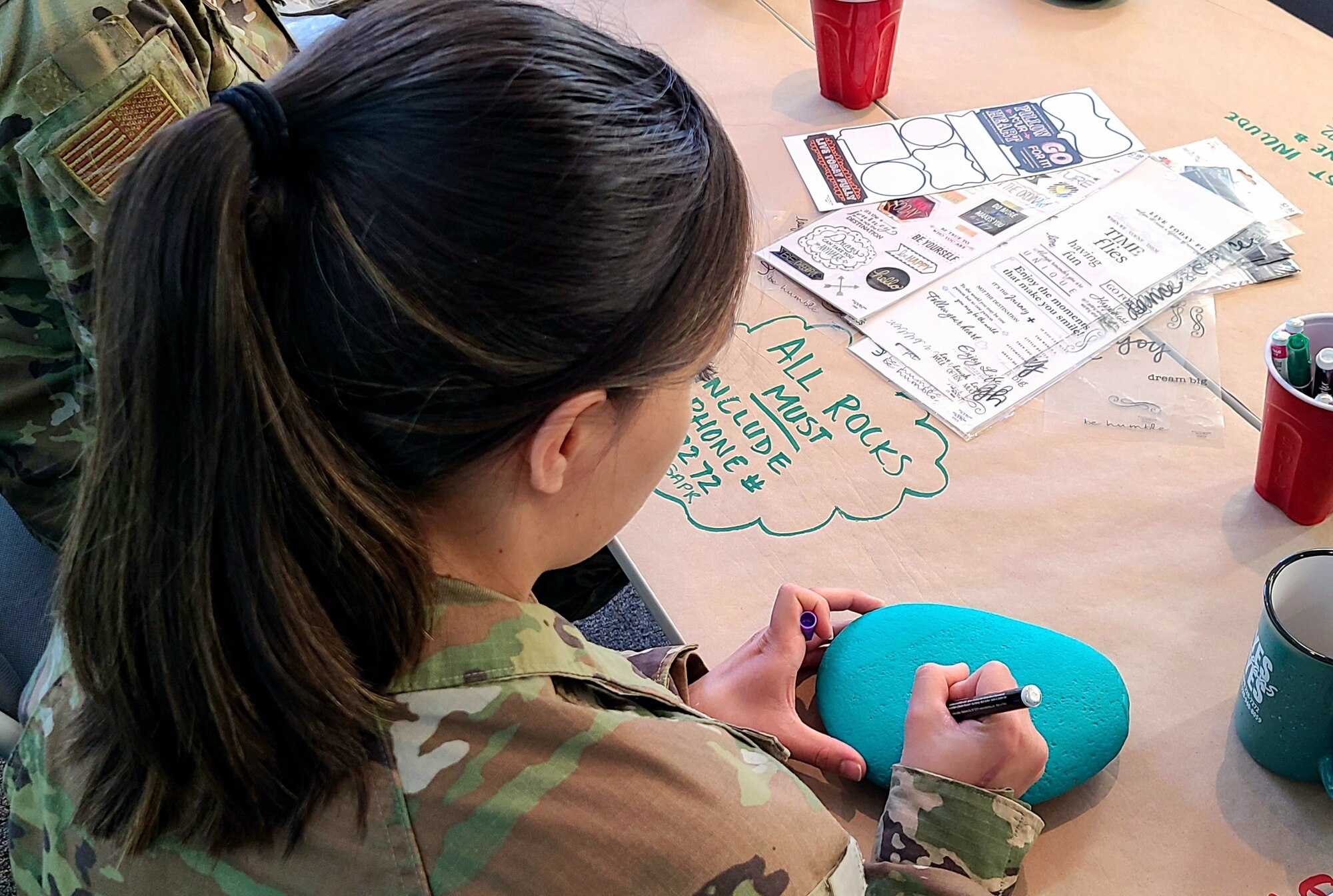 A photo of an Airman writing on a rock.