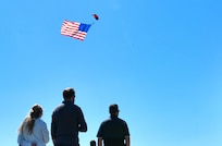 A member of the U.S. Army Special Operations Command parachute team, the Black Daggers, flies the American flag at the Titans of Flight Air Expo, Joint Base Charleston, South Carolina, April 8, 2022.