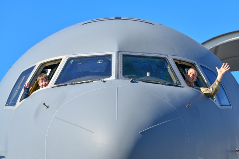 U.S. Air Force Capt. Ted Richard (right) and his son, Silas (left), wave from a KC-46 Pegasus at the Titans of Flight Air Expo, Joint Base Charleston, South Carolina, April 10, 2022.