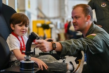 U.S. Air Force 1st Lt. Keith Silvin (right) instructs a young attendee how to use a virtual reality system controller at the titans of Flight Air Expo, Joint Base Charleston, South Carolina, April 8,2022.