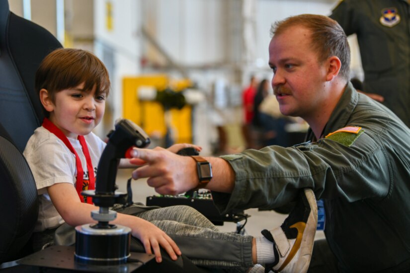 U.S. Air Force 1st Lt. Keith Silvin (right) instructs a young attendee how to use a virtual reality system controller at the titans of Flight Air Expo, Joint Base Charleston, South Carolina, April 8,2022.