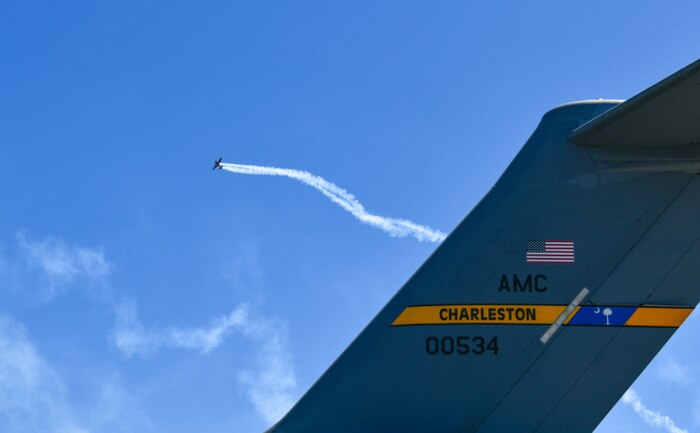 An Edge 540 performs an aerial maneuver past a C-17 Globemaster III at the Titans of Flight Air Expo, Joint Base Charleston, South Carolina, April 8,2022.