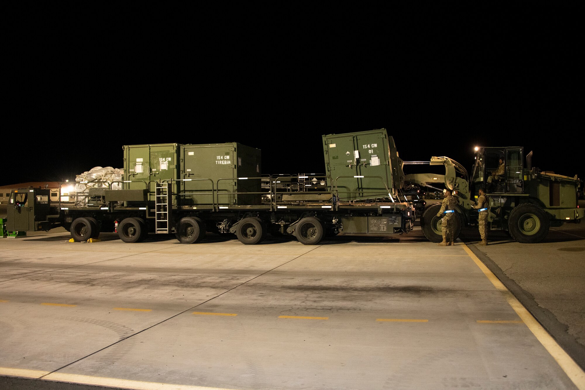 a large flat vehicle carries pallets in the middle of the night