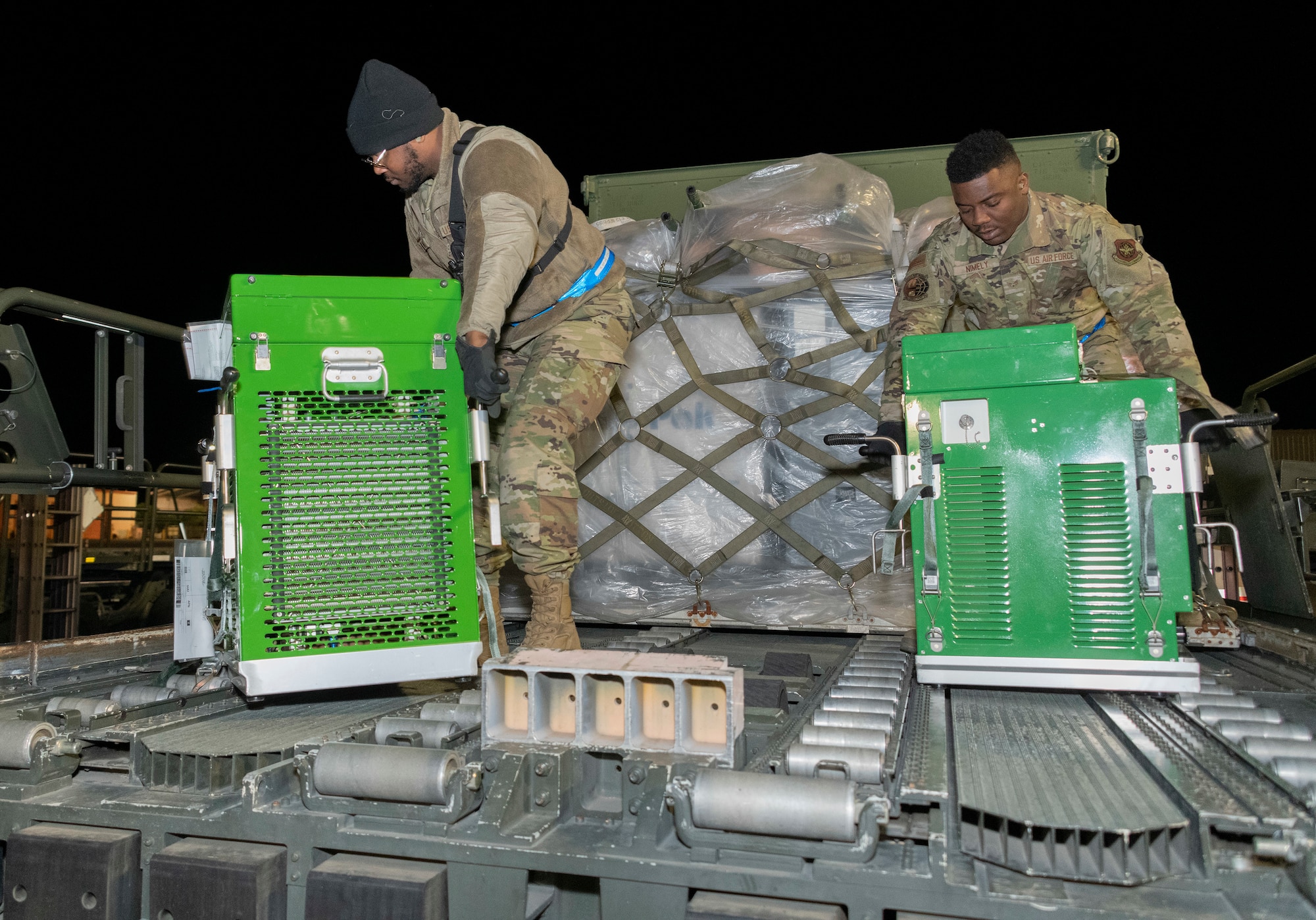 airmen move equipment on to an airplane