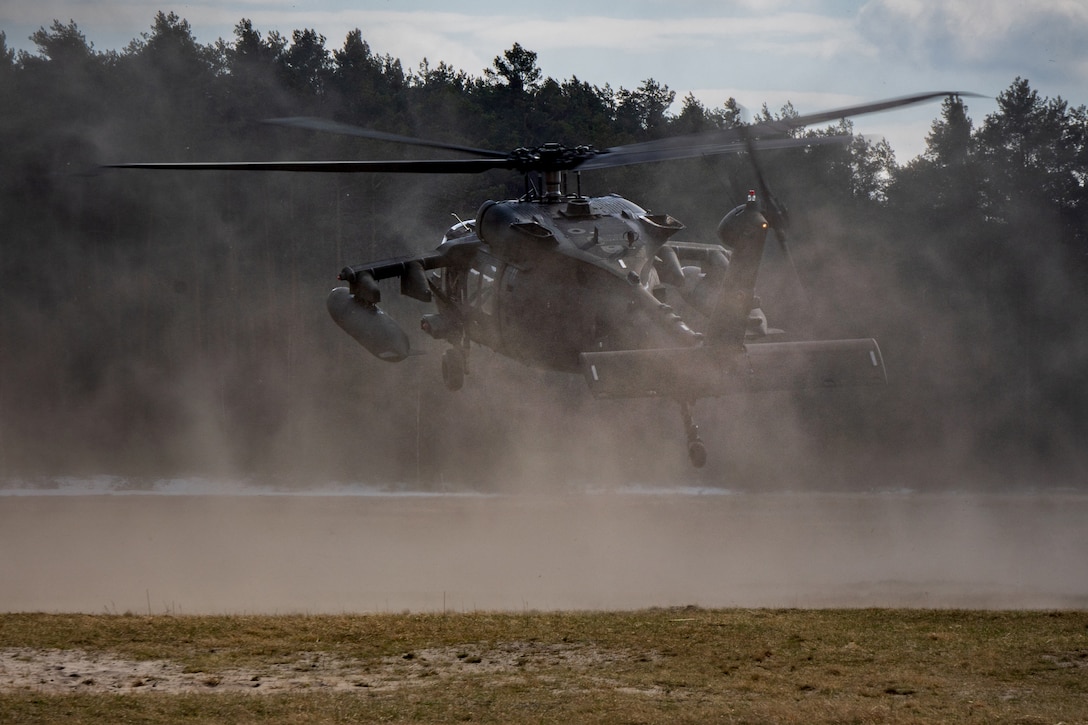 A helicopter kicks up dust as it lands.