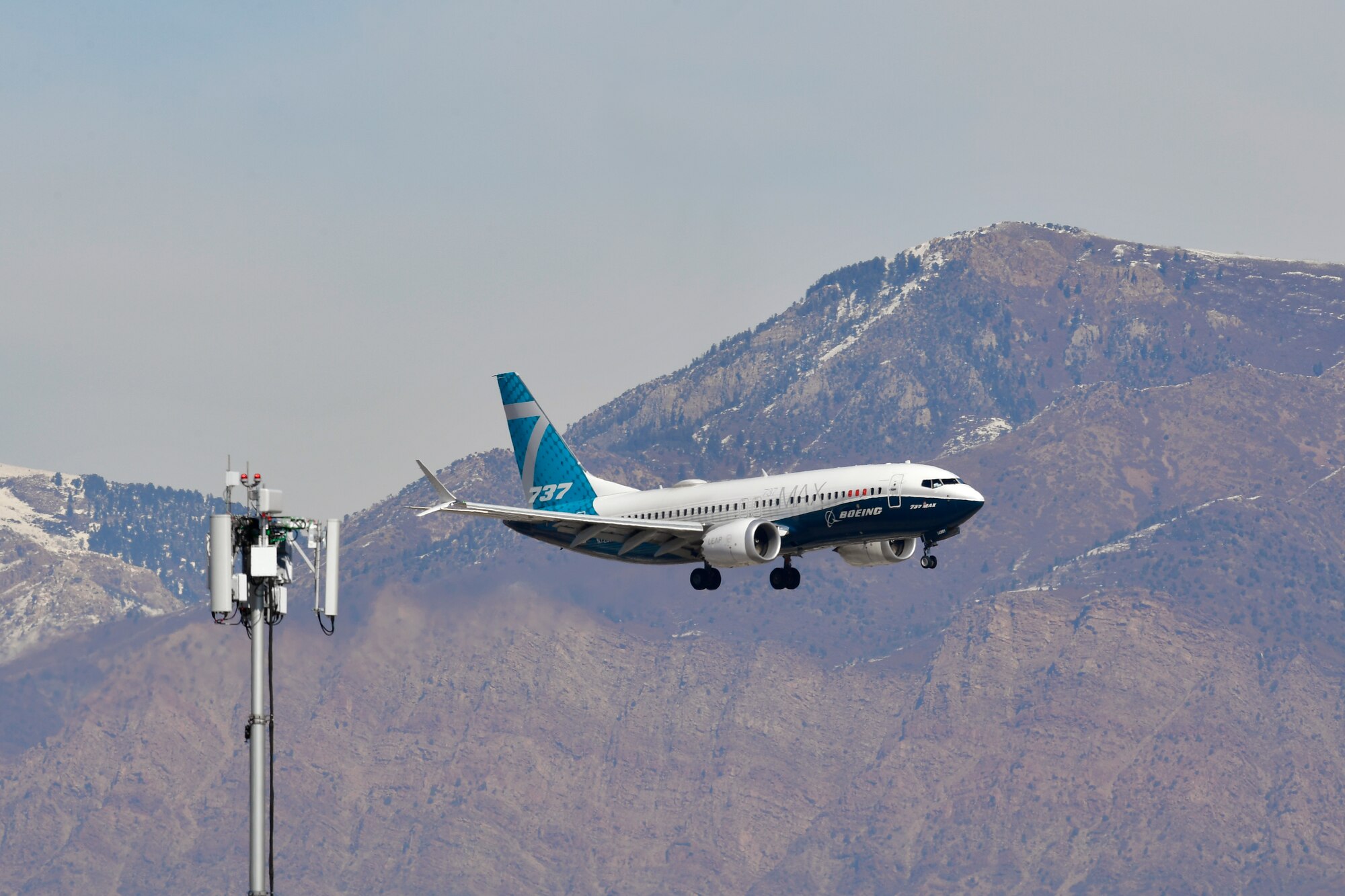 A Boeing 737 flies over the antenna of an 5G mobile test station with the Wasatch Mountains in the background.