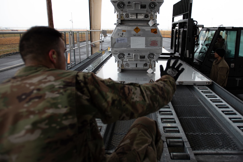 Military service members move pallets of equipment.