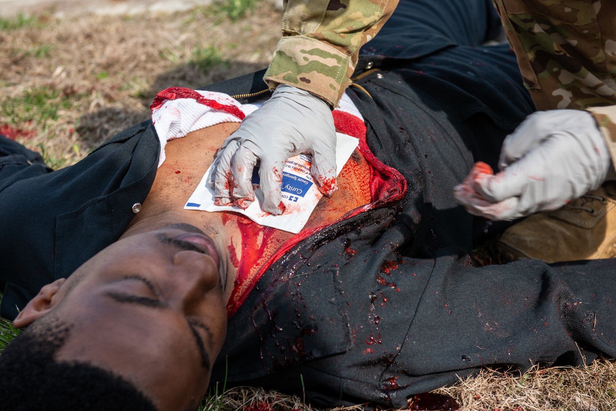 Staff Sgt. Adam Carroll, 51st Civil Engineer Squadron fire protection Airman, applies a quick-clotting bandage to a simulated gunshot wound on Tech. Sgt. Gerard Thomas, 51st Civil Engineer Squadron fire department station chief, during a national registry emergency medical technician training scenario at Osan Air Base, Republic of Korea, April 5, 2021.