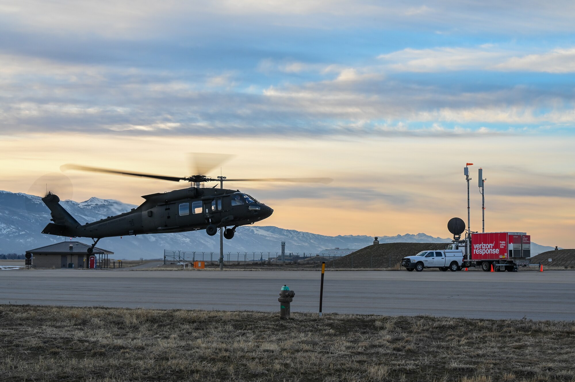 An UH-60 Blackhawk hovers above the airfield with the mobile test station in the background.