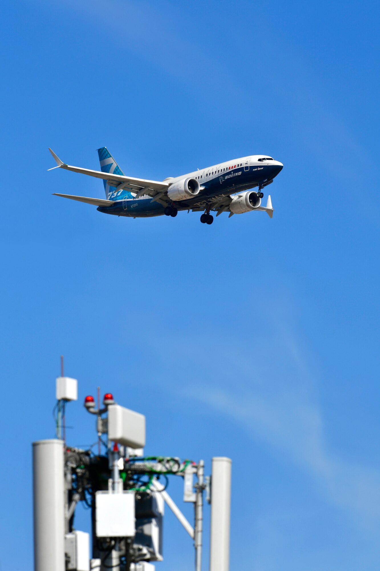 A Boeing 737 flies over the top of the antennae of a mobile test station in blue sky conditions.