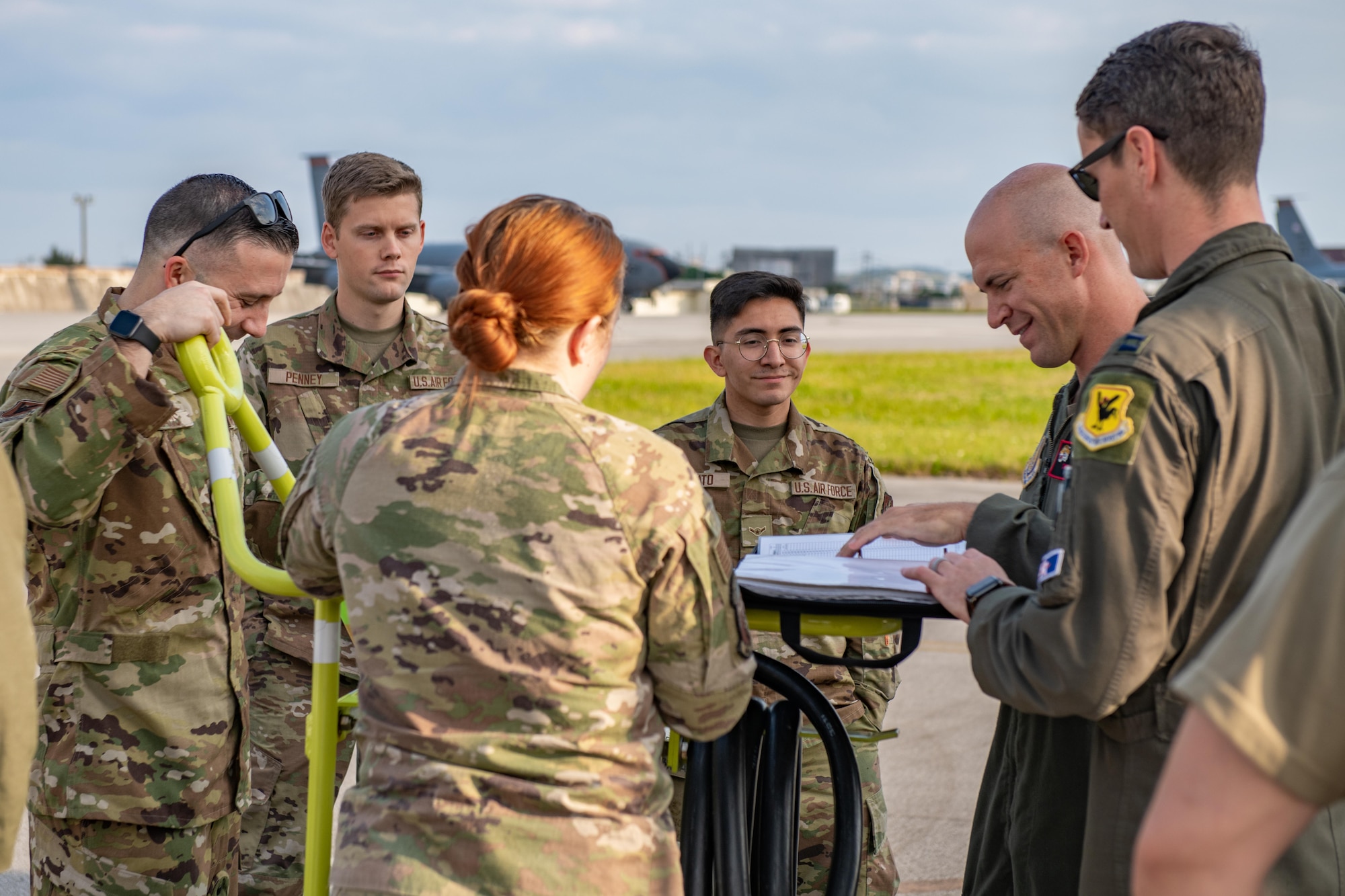A group of airmen stand around a commander for a flight in order to get the game plan for the day