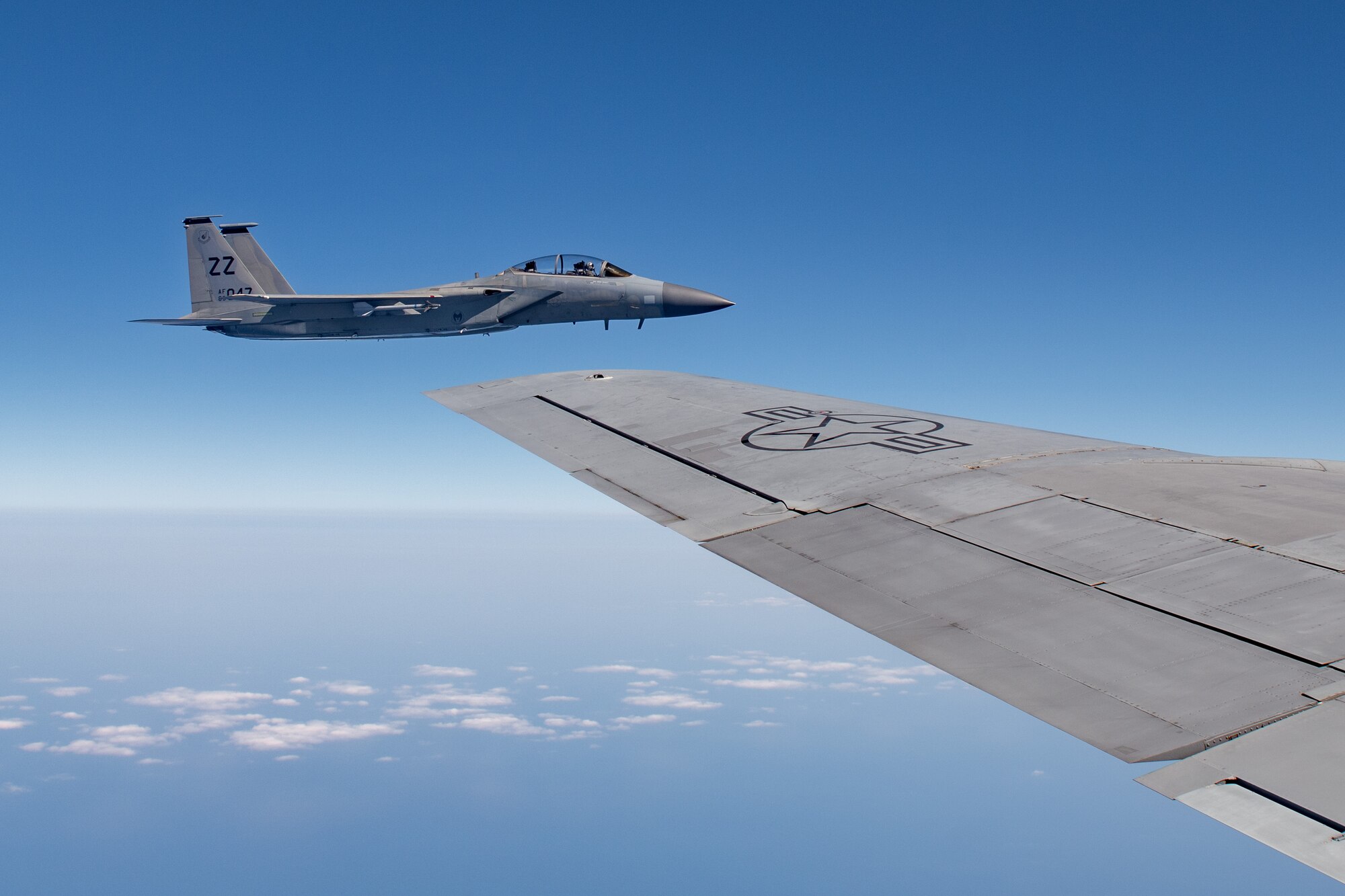 A fighter jet flies off the wing of a refueling plane
