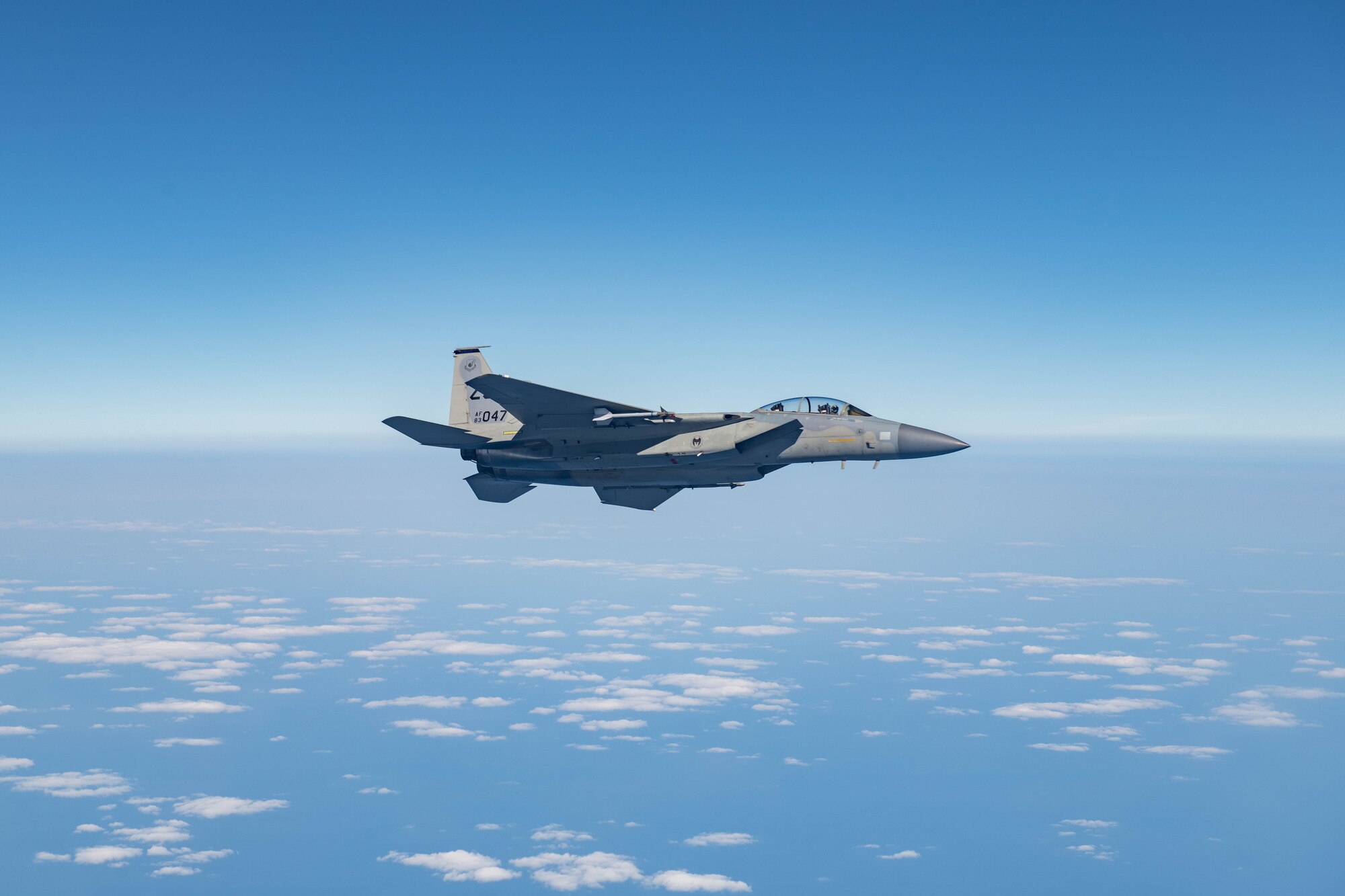 A fighter jet flies across the sky over the ocean