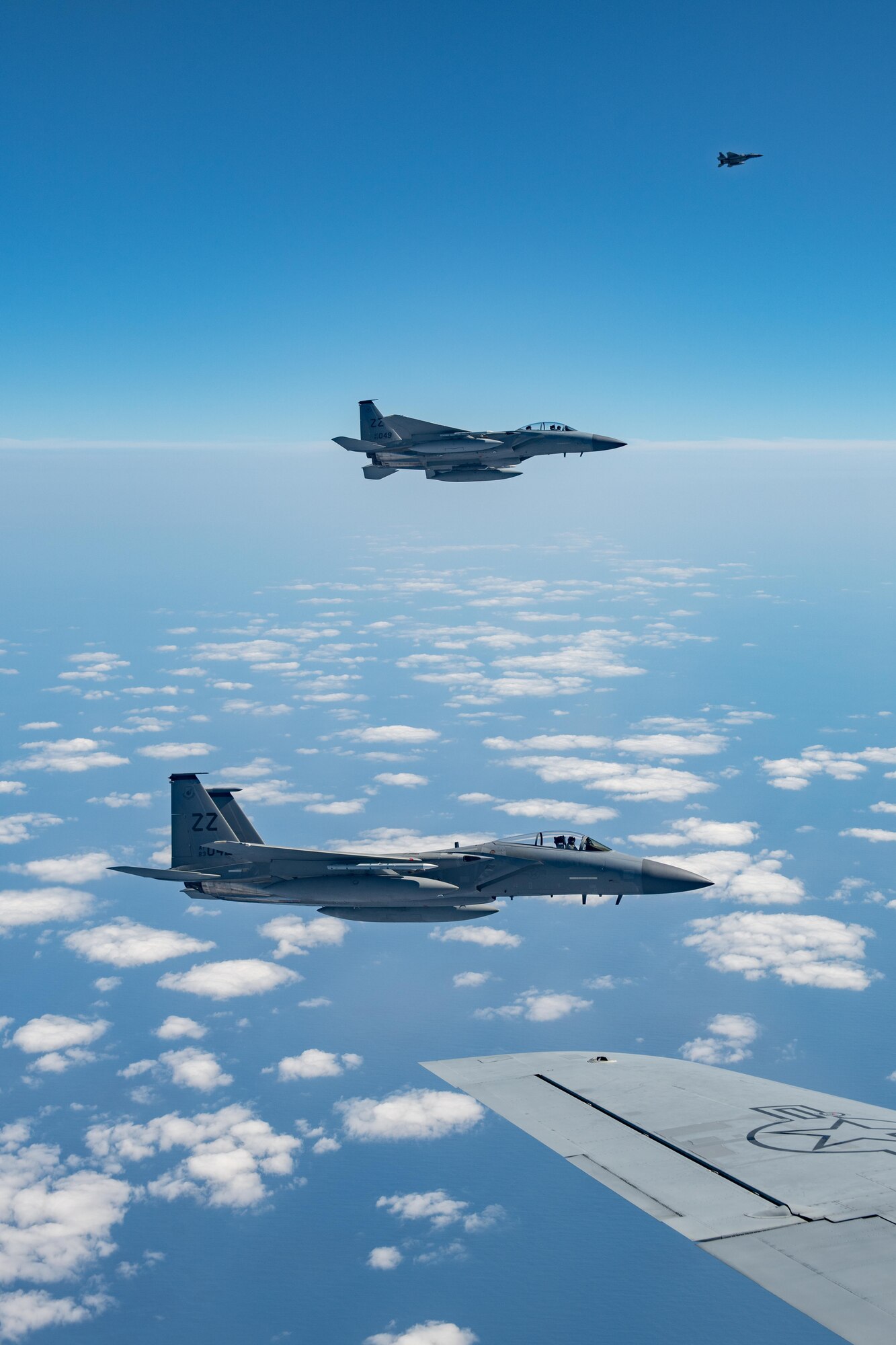 Three fighter jets fly off the side of a refueling plane