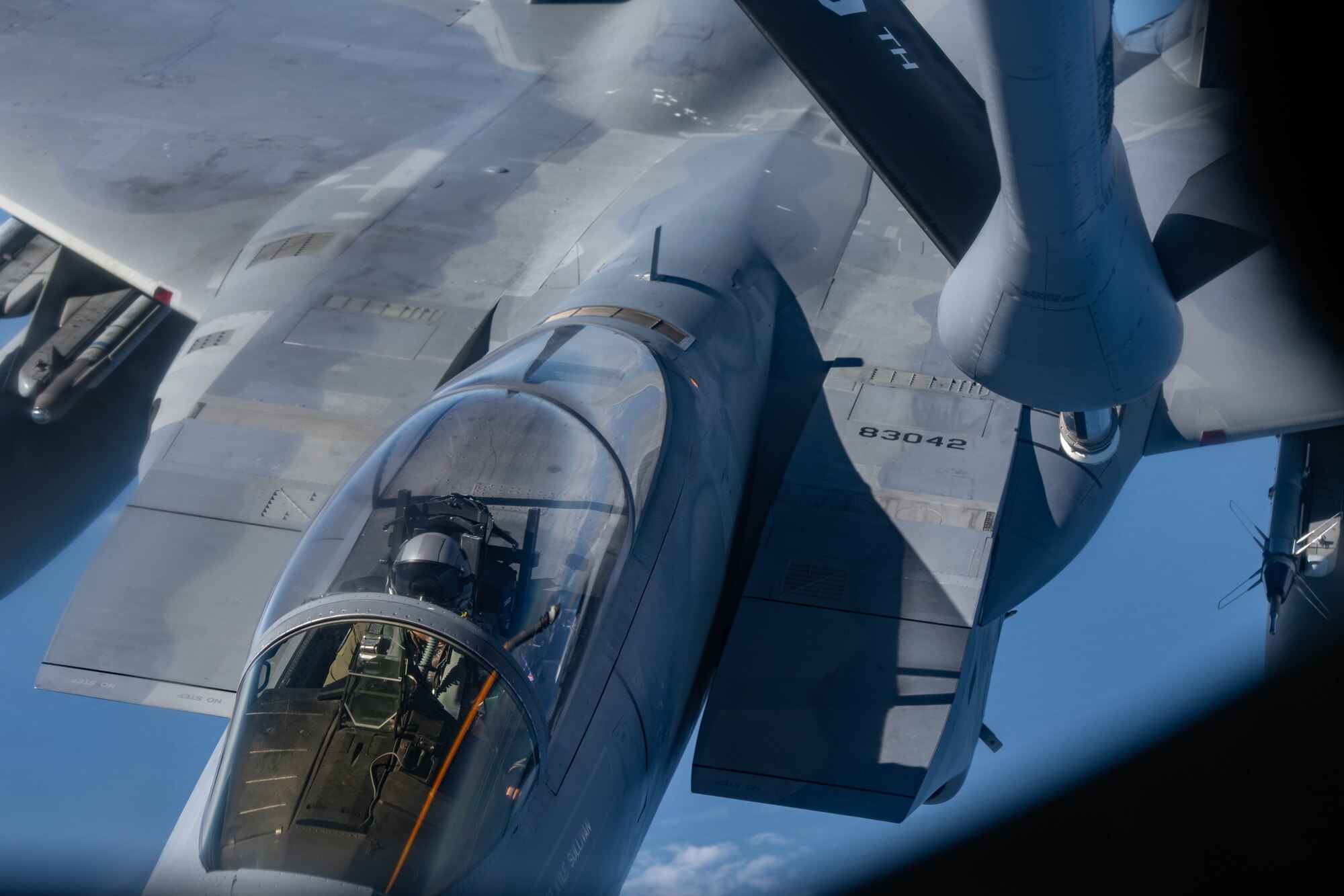 A fighter jet approaches a refueling jet to get refueled