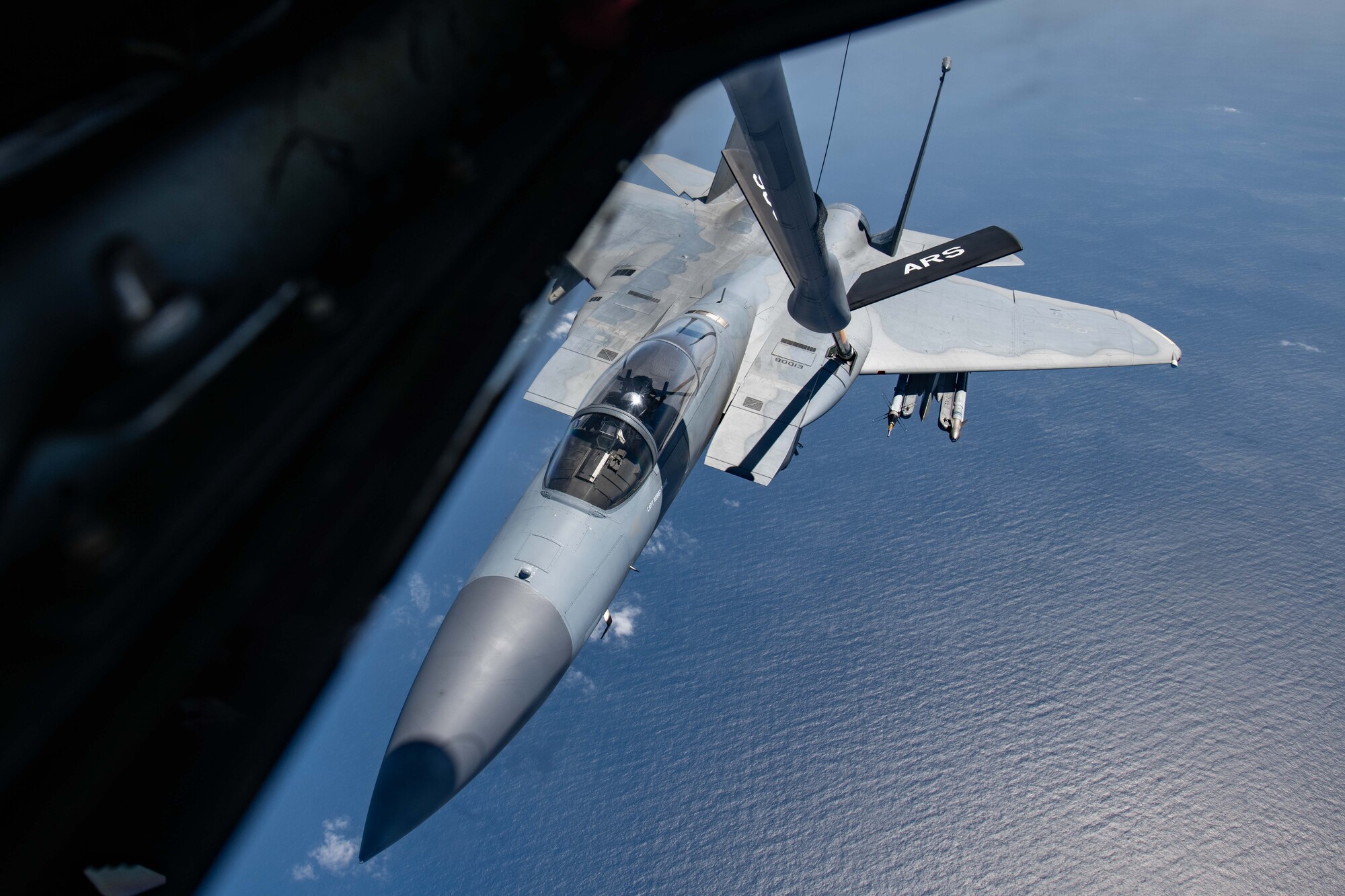 A fighter jet gets refueled by a KC-135 over the ocean