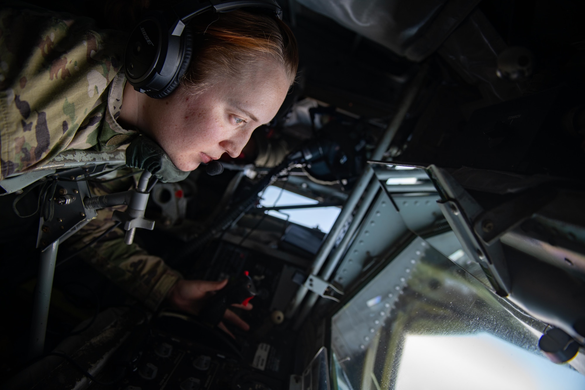 An airman stares out of the boom pod at the fighter jet she is refueling