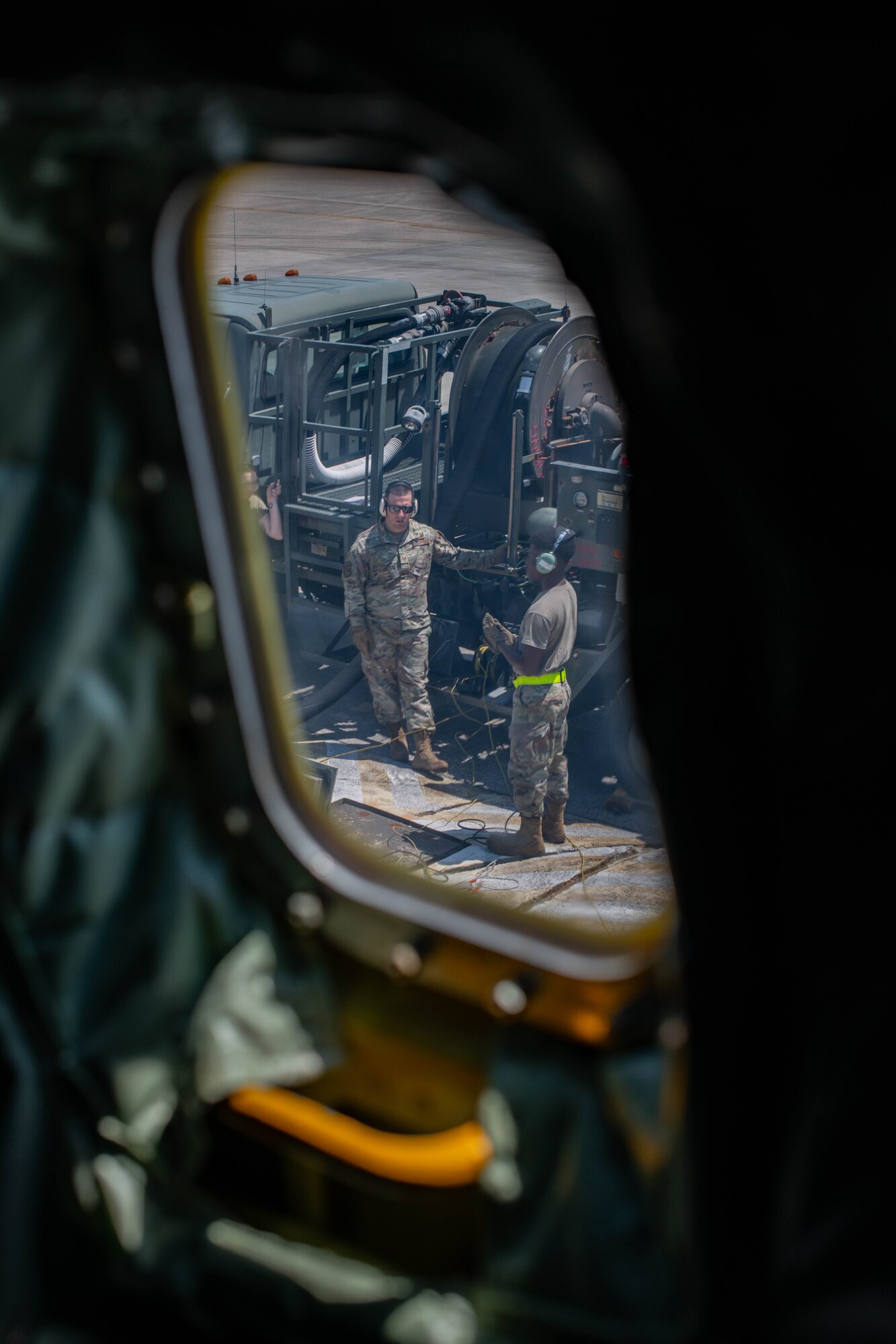 Two airmen stand by a refueling truck outside a plane